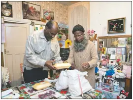  ??  ?? Sylius (left) and Bridgette Toussaint unpack their meals prepared by members of the Preston Windrush Covid Response team in Preston, England.