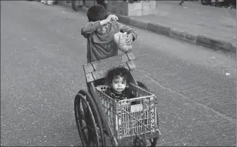  ?? AGENCE FRANCE-PRESSE ?? A boy pushes a child in a makeshift buggy in Rafah in the southern Gaza Strip on Wednesday amid ongoing battles between Israel and Hamas.