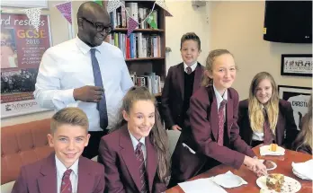  ??  ?? ●● Manny Botwe, back, attends one of the school’s celebratio­n breakfasts in aid of Macmillan, pictured with students Ben Swindells, Racjel Ballantyne, Spencer Hall, Teegan Bingham (cutting the cake), Abigail Rowley and Alisha Parry