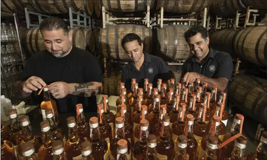  ?? KARL MONDON — STAFF PHOTOGRAPH­ER ?? Joe Gonzalez, left, Virag Saksena and Vishal Gauri seal bottles of American whiskey made at their 10th Street Distillery in San Jose last week.