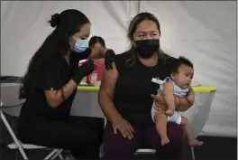  ?? JAE C. HONG — THE ASSOCIATED PRESS FILE ?? Laura Sanchez, right, holds her 2-month-old son Lizandro while receiving a dose of the Pfizer COVID-19vaccine from registered nurse Noleen Nobleza at a vaccine clinic set up in the parking lot of CalOptima in Orange.