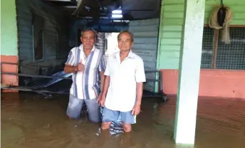  ??  ?? Wan Juk (right) and another villager show their longhouse which was flooded since Sunday.