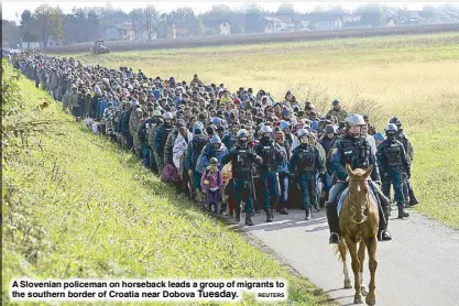  ?? REUTERS ?? A Slovenian policeman on horseback leads a group of migrants to the southern border of Croatia near Dobova Tuesday.