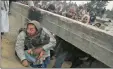  ?? PICTURE: AP ?? SPLITTING THE CITY: A Palestinia­n man holds a baby as he crawls under a border barrier between Egypt and Gaza in Rafah.