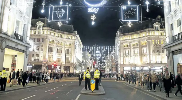  ?? ALASTAIR GRANT/ THE ASSOCIATED PRESS ?? Police officers and members of the public walk near Oxford Circus subway station in the west of London after it was reopened Friday.