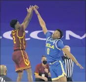  ??  ?? USC guard Tahj Eaddy, left, shoots the winning 3-point shot over UCLA guard Jaylen Clark’s outstretch­ed hand.