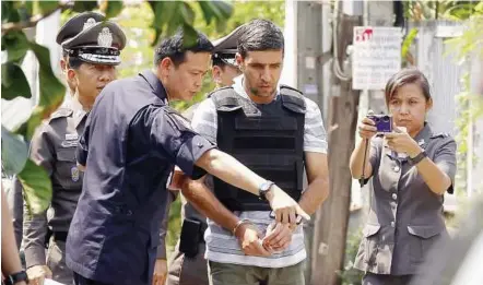  ??  ?? Explosive matters: Thai police officers questionin­g Khazaei during a crime re-enactment outside the rented house where the explosive devices exploded in central Bangkok yesterday. — EPA