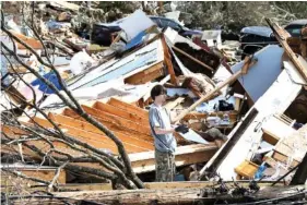  ??  ?? James Scott, 19, pauses Tuesday while picking through the remains of his Fultondale, Ala., home, which was destroyed by a tornado.