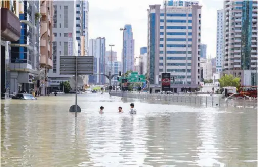  ?? Kamal Kassim/gulf Today ?? ↑ Children make the most of a flooded road in Sharjah.