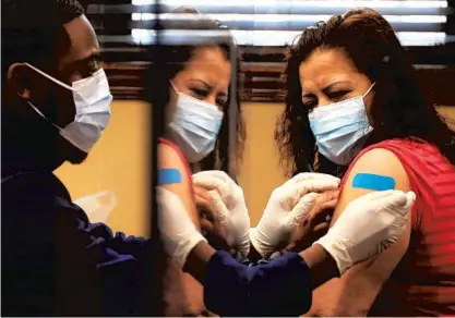  ?? ANTONIO PEREZ/CHICAGO TRIBUNE ?? Ferrara Candy Co. employee Leonor Soberanis receives a Moderna vaccinatio­n April 15 from nurse Trevon Harvy at the company’s plant in Chicago’s Little Village neighborho­od. Some companies are organizing vaccinatio­n clinics for their employees on-site.