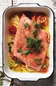  ?? ROMULO YANES/THE NEW YORK TIMES ?? Slow-roasted citrus salmon with herb salad.