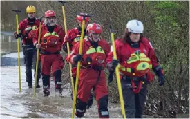  ?? ?? Search: Emergency workers scour the flooded fields yesterday