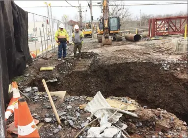  ?? EVAN BRANDT — MEDIANEWS GROUP ?? Workers survey the gash cut into the soil by water gushing from a main break at the King Street bridge in Pottstown on Wednesday.