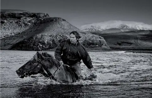  ??  ?? Hochweide Landmannaa­fréttur, Island Kristinn Guðnason durchquert den Fluss Eystri-Rangá mit seinem Pferd Eldur. © Ragnar Axelsson/ Knesebeck Verlag