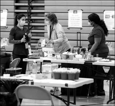  ?? STEVE MARCUS ?? Southern Nevada Health District workers set up for a COVID-19 pop-up vaccinatio­n clinic Jan. 29 at Jerome Mack Middle School.