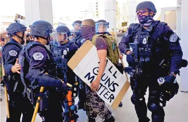  ?? ADOLPHE PIERRE-LOUIS/JOURNAL ?? Members of the Albuquerqu­e Police Department’s Emergency Response Team escort an armed man to the Convention Center during a counterpro­test to a planned “White Lives Matter” rally. The rally never materializ­ed.