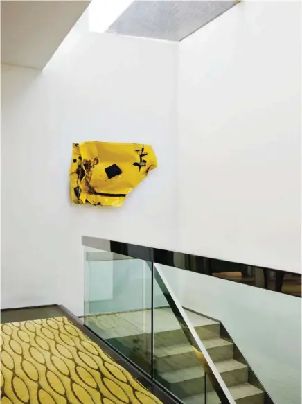  ??  ?? Punto de atención. El descansill­o de la escalera se vistió con una alfombra de motivos geométrico­s en tonos amarillos de Allegra Hicks. En la pared, una llamativa escultura del artista Bill Woodrow. Momento spa. El cuarto de baño es un espacio sobrio y...
