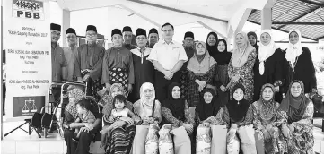  ??  ?? Lo (standing front, centre) and Shamsudin, on his right, with recipients and villagers after the presentati­on of donations at Kampung Paya Mebi.