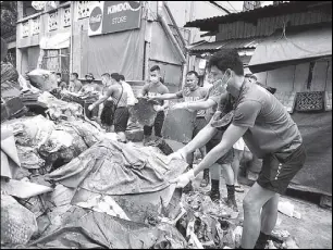  ?? BOY SANTOS ?? Members of the Eastern Police District collect trash yesterday after monsoon rains caused flooding along C-5 Road in Marikina City.