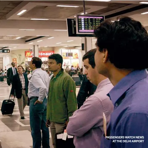  ?? AP PHOTO ?? PASSENGERS WATCH NEWSATTHE DELHI AIRPORT