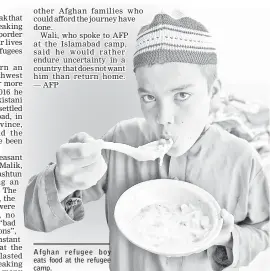  ??  ?? Afghan refugee boy eats food at the refugee camp.