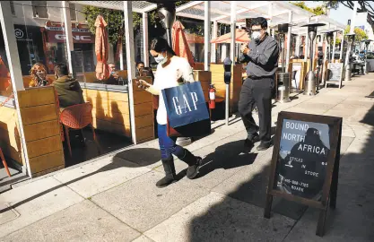  ?? Scott Strazzante / The Chronicle ?? Shoppers stroll past outdoor diners Thursday at Delarosa on S.F.’s Chestnut Street. San Francisco is one of seven counties under yellowtier rules starting Thursday.