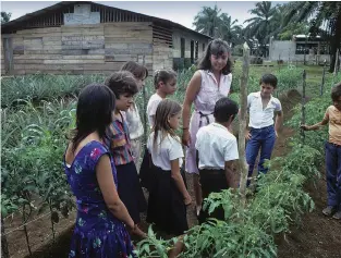  ??  ?? Peace Corps volunteer Marya
Cota-Wilson gives a gardening lesson in Costa Rica in
the 1980s.