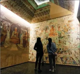  ?? GAO ZHAN / CHINA NEWS SERVICE ?? Tourists in Lanzhou, Gansu province, take in a copy of a mural from the Dunhuang Mogao Grottoes in May 2020.