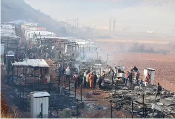  ??  ?? Syrian refugees check the damage following a fire that ripped through their refugee camp in the village of Yammouneh in Lebanon’s eastern Bekaa Valley. — AFP photo