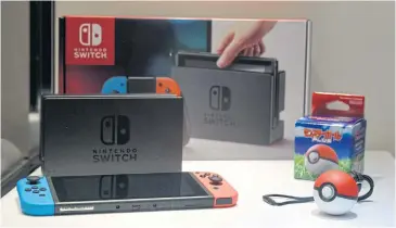  ?? BLOOMBERG ?? A Switch video game console, left, and a Poke Ball Plus controller are displayed at an unveiling event in Tokyo yesterday.