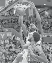  ?? Sue Ogrocki / Associated Press ?? Rockets center Clint Capela dunks over Thunder forward Paul George for two of his 10 points.