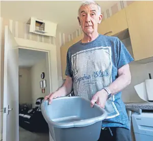  ?? Picture: Kris Miller. ?? Grant Grassie empties a basin used to collect water at his sister’s flat after it started pouring through the ceiling.