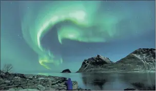  ?? OLIVIER MORIN — AFP/GETTY IMAGES ?? A person watches the northern lights in 2018 in Utakleiv in the Lofoten islands of northern Norway within the Arctic Circle.