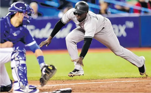  ?? FRANK GUNN / THE CANADIAN PRESS ?? New York Yankees shortstop Didi Gregorius slides safely into home ahead of the tag by Toronto Blue Jays catcher Luke Maile on a double by Yankees outfielder Aaron Hicks Thursday night at the Rogers Centre.