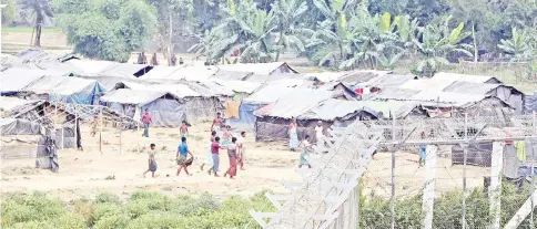  ?? — Reuters photo ?? File photo shows Rohingya people who fled from their towns after the violence in the state of Rakhine walking behind a fence on the border line outside Maungdaw, Myanmar.