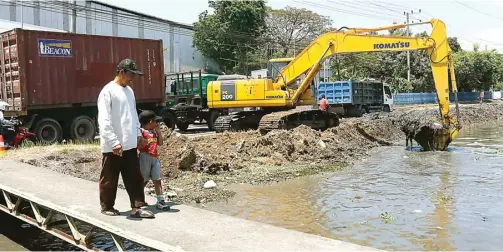  ?? ALFIAN RIZAL/JAWA POS ?? ANGKUT LUMPUR: Petugas DPUBMSDA Sidoarjo melakukan normalisas­i Sungai Mangetan Kanal kemarin. Mereka mengeruk sungai di kawasan Keboansike­p, Gedangan.