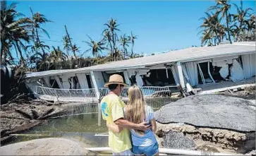  ??  ?? BROOKE GILBERT, 15, and her father, Mike Gilbert, examine her grandparen­ts’ collapsed condo complex in Islamorada. “This is where I learned to swim, where I learned to drive a boat,” said Brooke, holding back tears.