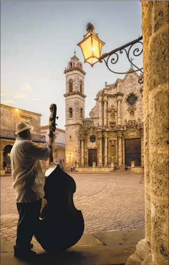  ?? Buena Vista Images / Getty Images ?? MUSICIANS are everywhere in Havana, like this man playing double bass in Plaza de la Cathedral.