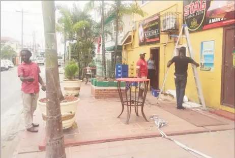  ??  ?? Proprietor Jermaine Langevine (standing at left) overseeing his staff as they made preparatio­ns yesterday morning to operate the business on his parapet.