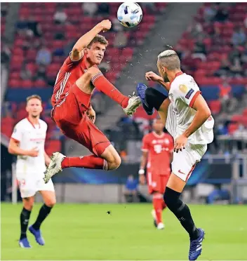  ?? FOTO: AP/TIBOR ILYES ?? Bayerns Thomas Müller im Zweikampf mit Joan Jordán vom FC Sevilla. Die Partie in der ungarische­n Hauptstadt Budapest fand keinen Sieger in der regulären Spielzeit.