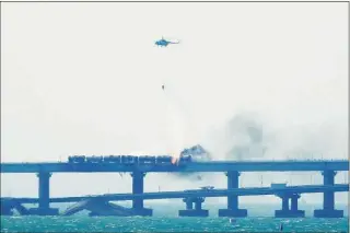  ?? AFP / TNS ?? A firefighti­ng helicopter pours water on the carriages of a train on fire on the Kerch bridge linking Crimea to Russia, after a truck exploded on Saturday.