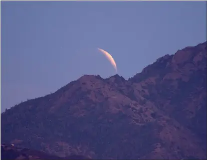  ?? JOEL ROSENBAUM — THE REPORTER ?? Obscured by the clouds, the Super Flower Blood Moon is cast in the reddish shadow as the Earth passes across its face as it climbs above Mt. Diablo in Contra Costa County on Sunday. According to the Farmer’s Almanac, the full moon in May is known as the “Flower Moon” due to the fact that flowers are abundant everywhere during this time. Other names include the Full Corn Planting Moon or the Milk Moon.