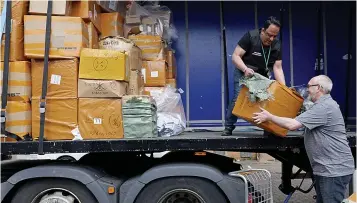  ??  ?? On the back of a lorry...trading standards’Tariq Mohammed, left, loads trailer with raid haul