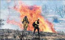  ?? NICK UT/AP ?? Firefighte­rs turn away from a flare-up of a wildfire near Acton, Calif., on Monday.