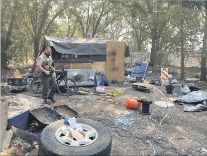  ?? PHOTOS BY JIM SMITH — DAILY DEMOCRAT ?? HOST officer James Olsen surveys a homeless camp off Hwy. 113 in northern Woodland.