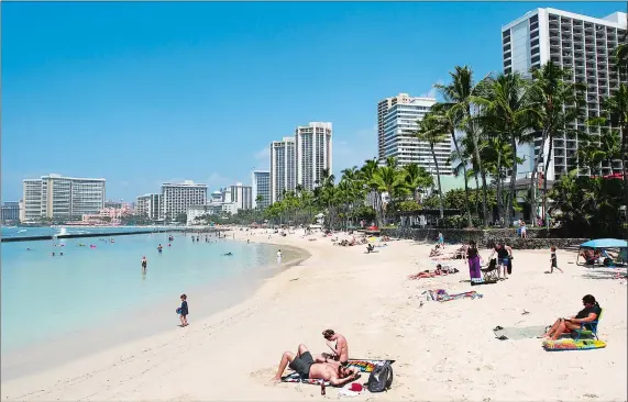  ?? CALEB JONES/AP PHOTO ?? People relax on the beach in Waikiki in Honolulu in March. Many Americans might dream of going on vacation to places such as Waikiki, but a new poll shows nearly half of Americans won’t be taking a summer vacation this year, mostly because they can’t...