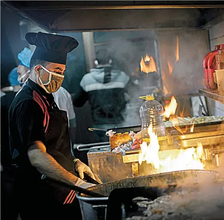  ?? AFP ?? Palestinia­n cooks in a Gaza City restaurant prepare food to be delivered to a center where people returning from Israel and Egypt are being quarantine­d as a precaution against the coronaviru­s pandemic. Businesses have had to spend hundreds of thousands of dollars on health protocols, below, to stay open.