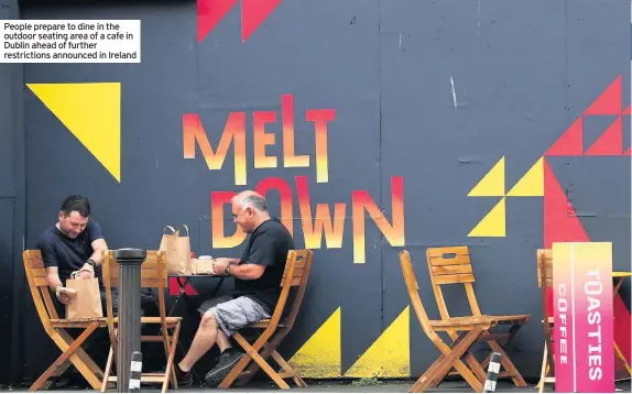  ??  ?? People prepare to dine in the outdoor seating area of a cafe in Dublin ahead of further restrictio­ns announced in Ireland