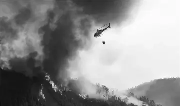  ??  ?? A helicopter overfly a wildfire in Carvalho, next to Pampilhosa da Serra. — AFP photo