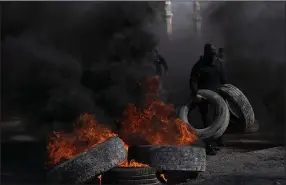  ?? (AP/Nasser Nasser) ?? Palestinia­n protesters block the main road with burning tires in the West Bank city of Jericho on Monday.